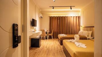 Una habitación de hotel con cama, escritorio, silla, televisor y minibar.