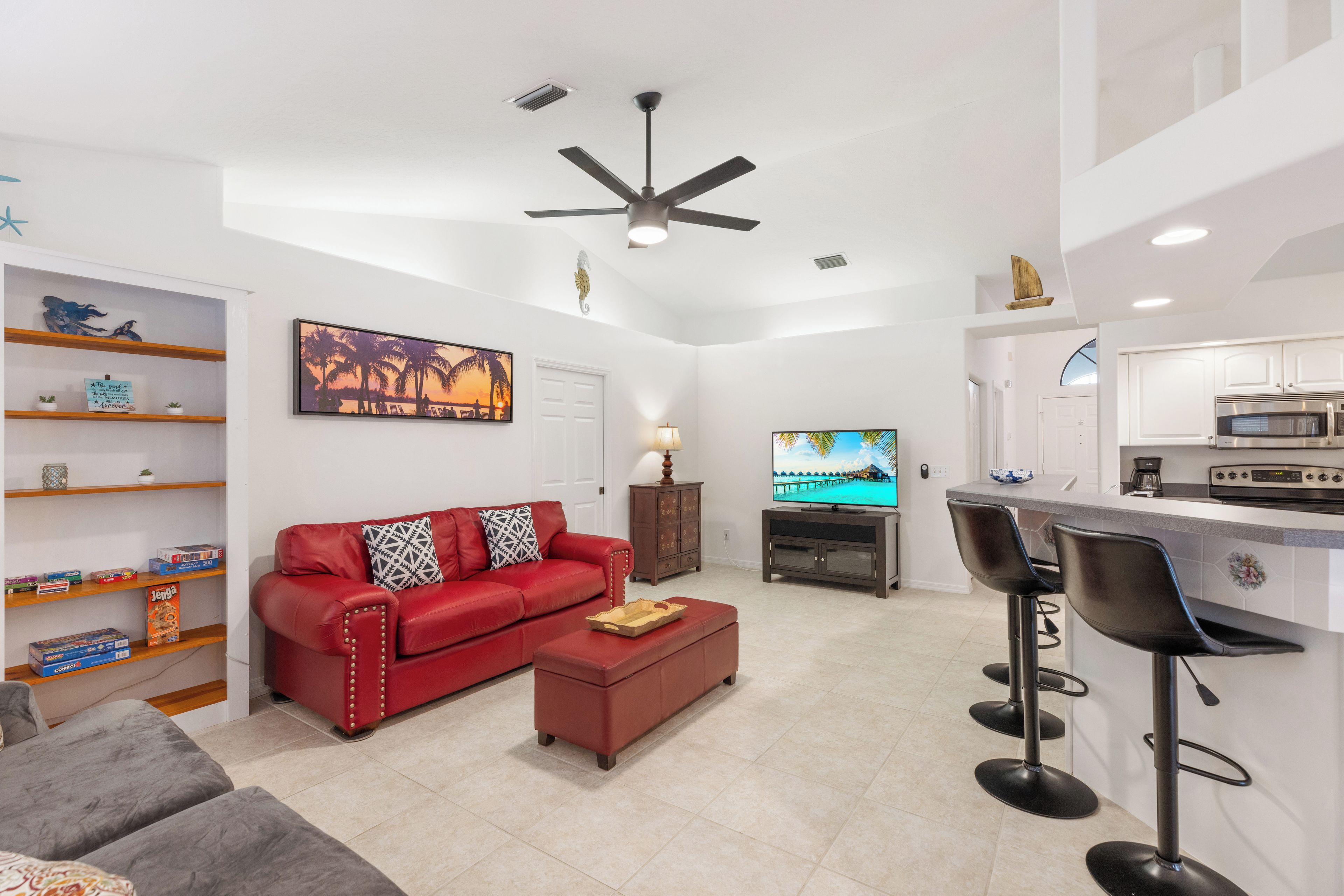 A modern living room with a red sofa, a coffee table, a TV, and a kitchen area with a bar.