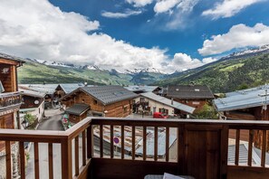 Un bâtiment en bois doté d’un balcon donnant sur un village et des montagnes.