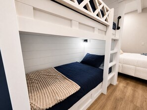 Una cama litera con cabecera, una mesita de noche y un pequeño estante.
