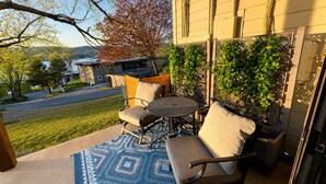 Un patio al aire libre con una mesa y sillas, un tapete estampado y vista a un edificio y árboles.
