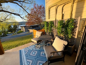 Un patio al aire libre con una mesa y sillas, un tapete estampado y vista a un edificio y árboles.