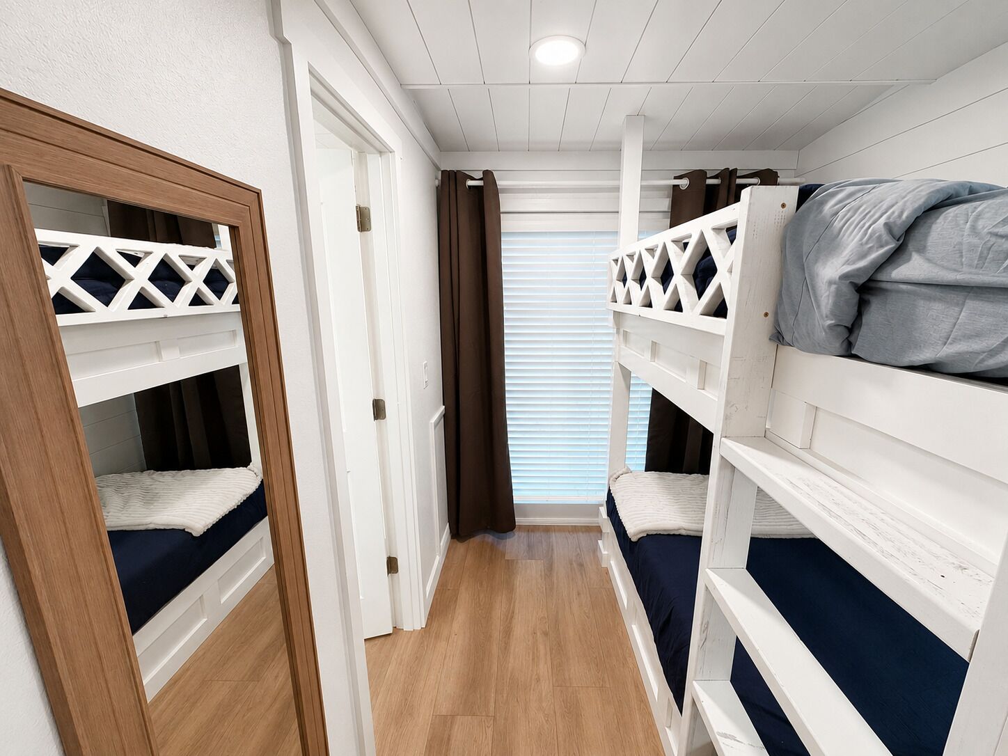 Ein Zimmer mit Etagenbetten, Holzboden und einem Fenster mit Jalousien.