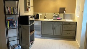 A compact kitchen with white cabinets, a built-in microwave, and a small refrigerator. - Le Petit Pavillon, located in the heart of the Anjou vineyards between Angers and Saumur (Tuffalun)