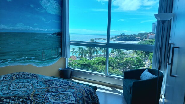 Een slaapkamer met een groot raam dat uitzicht biedt op de oceaan en de skyline.