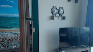 Een moderne woonkamer met een grote flatscreen televisie, een houten tv-meubel en decoratieve wandkunst.