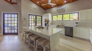 Une cuisine spacieuse dotée d’un grand îlot central, de tabourets de bar et d’un ventilateur de plafond.