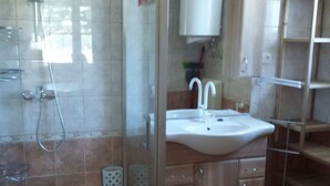 A bathroom with a glass-enclosed shower, a sink, and wooden cabinets. - Comfortable vacation home in a quiet area close to Lake Balaton (Szántód)