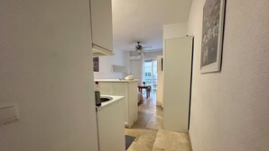 A narrow hallway leading to a kitchen with a built-in sink and a dining area with a table and chairs. - Studio in the center of Malaga (Málaga)