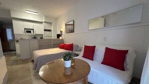 A compact room with a bed, a white sofa, a small table, and a kitchenette. - Studio in the center of Malaga (Málaga)