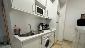 A compact kitchen with a built-in washing machine, a microwave, and a sink. - Studio in the center of Malaga (Málaga)