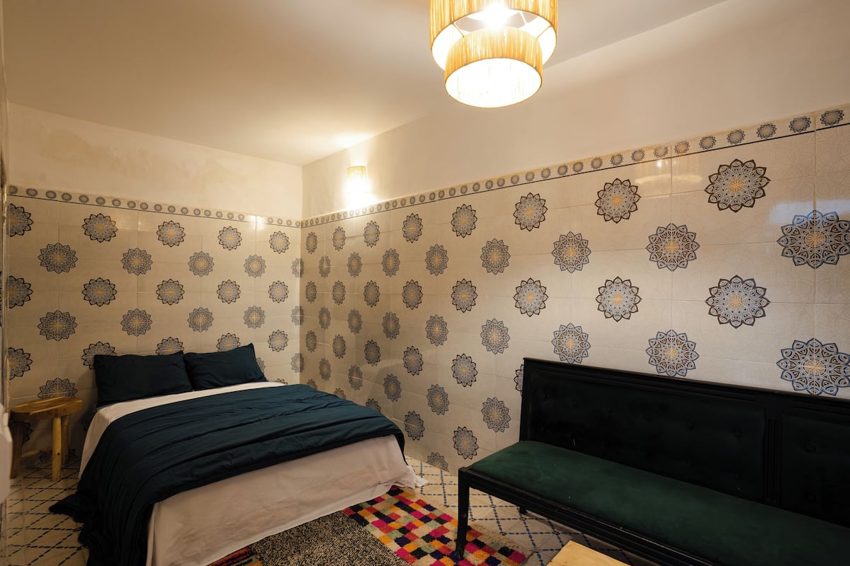 Une chambre à coucher avec un lit, un banc et des murs à motifs.