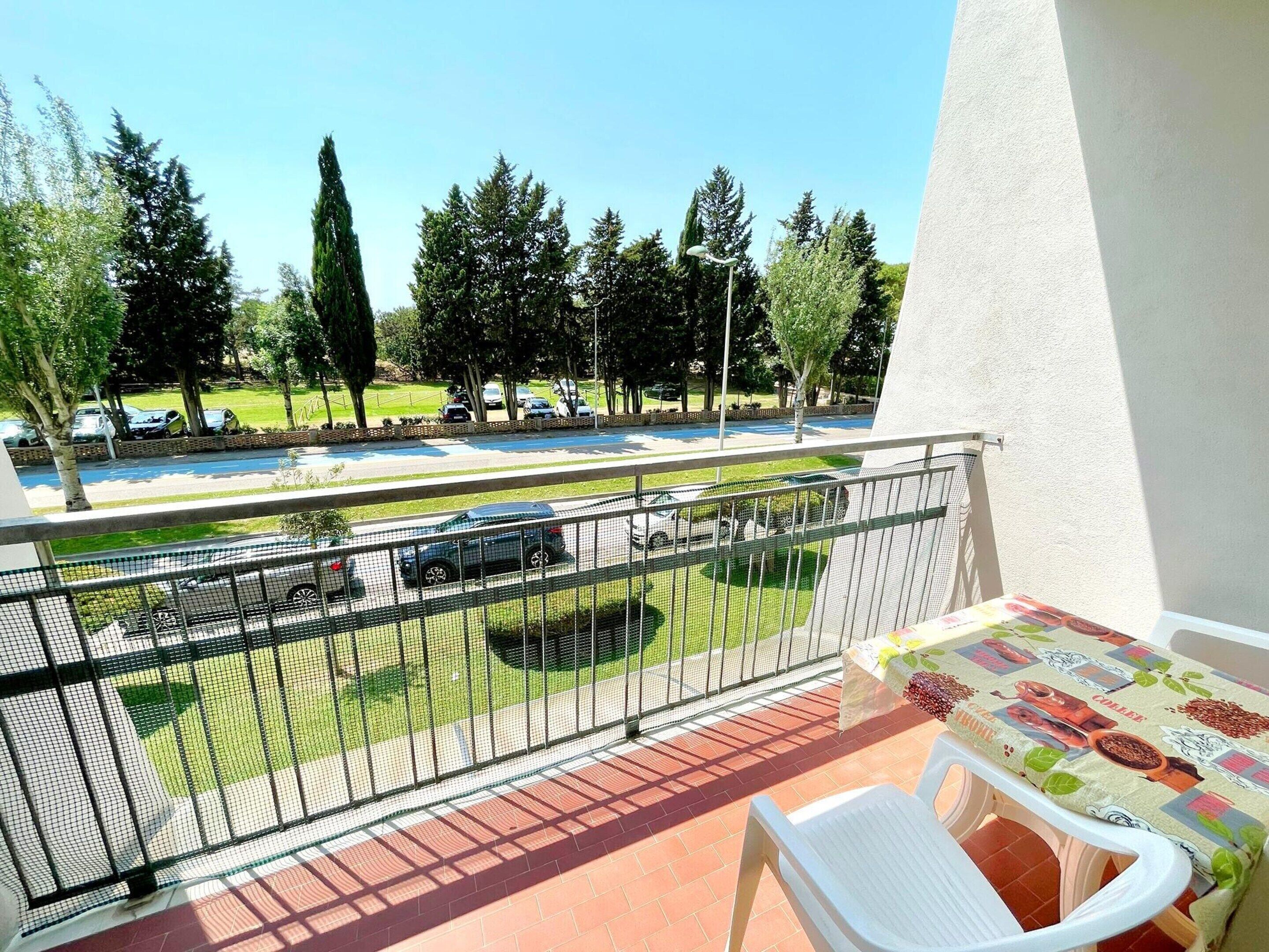 A balcony with a view of a parking lot and trees.