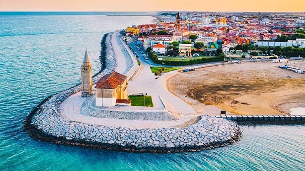 Un pueblo costero con una iglesia destacada, un paseo marítimo y una zona de playa.