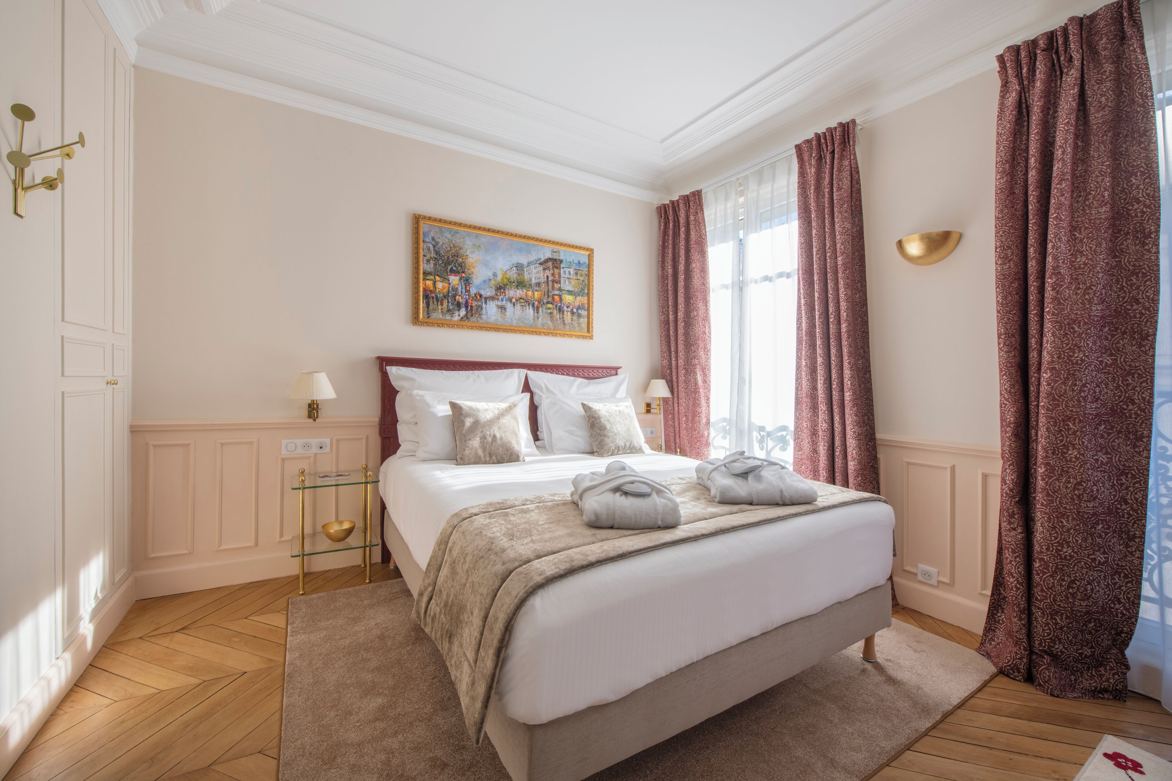 A hotel room with a large bed, a painting on the wall, and a window with curtains.
