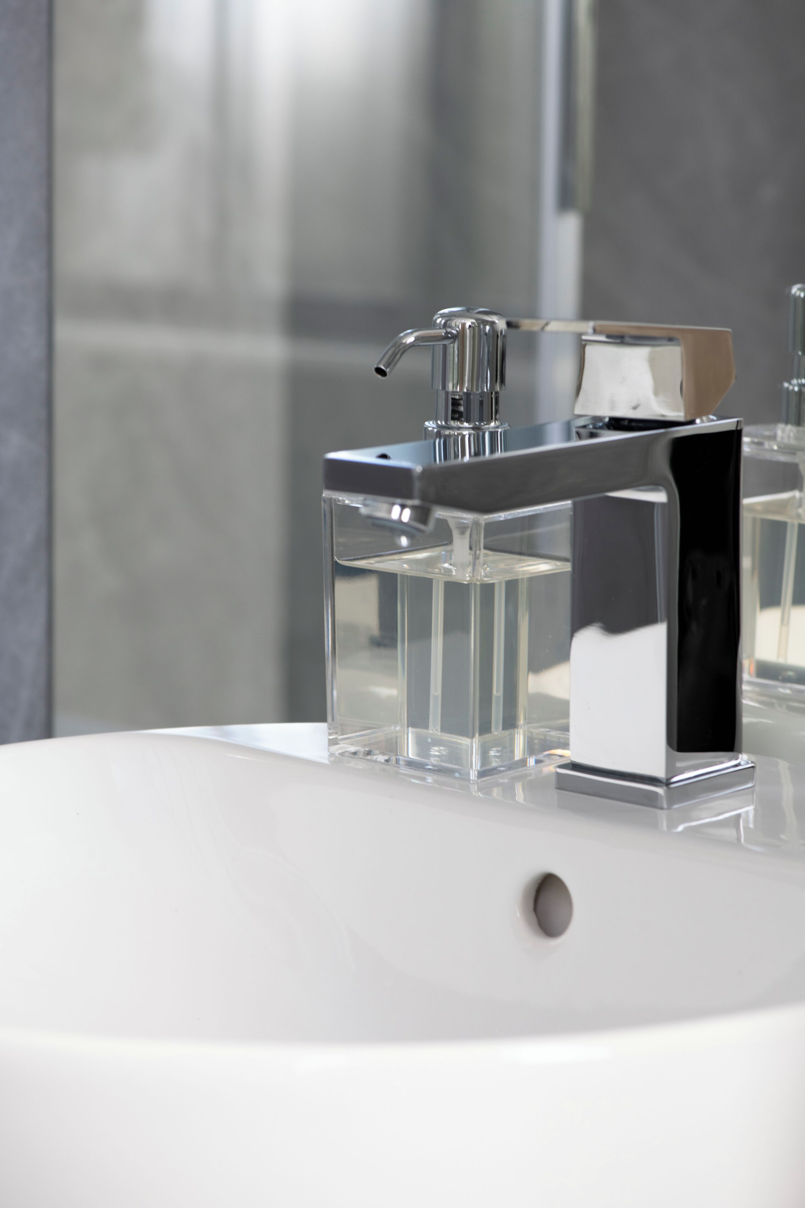 Une salle de bain moderne avec un robinet chromé, un récipient en verre transparent et un lavabo blanc.