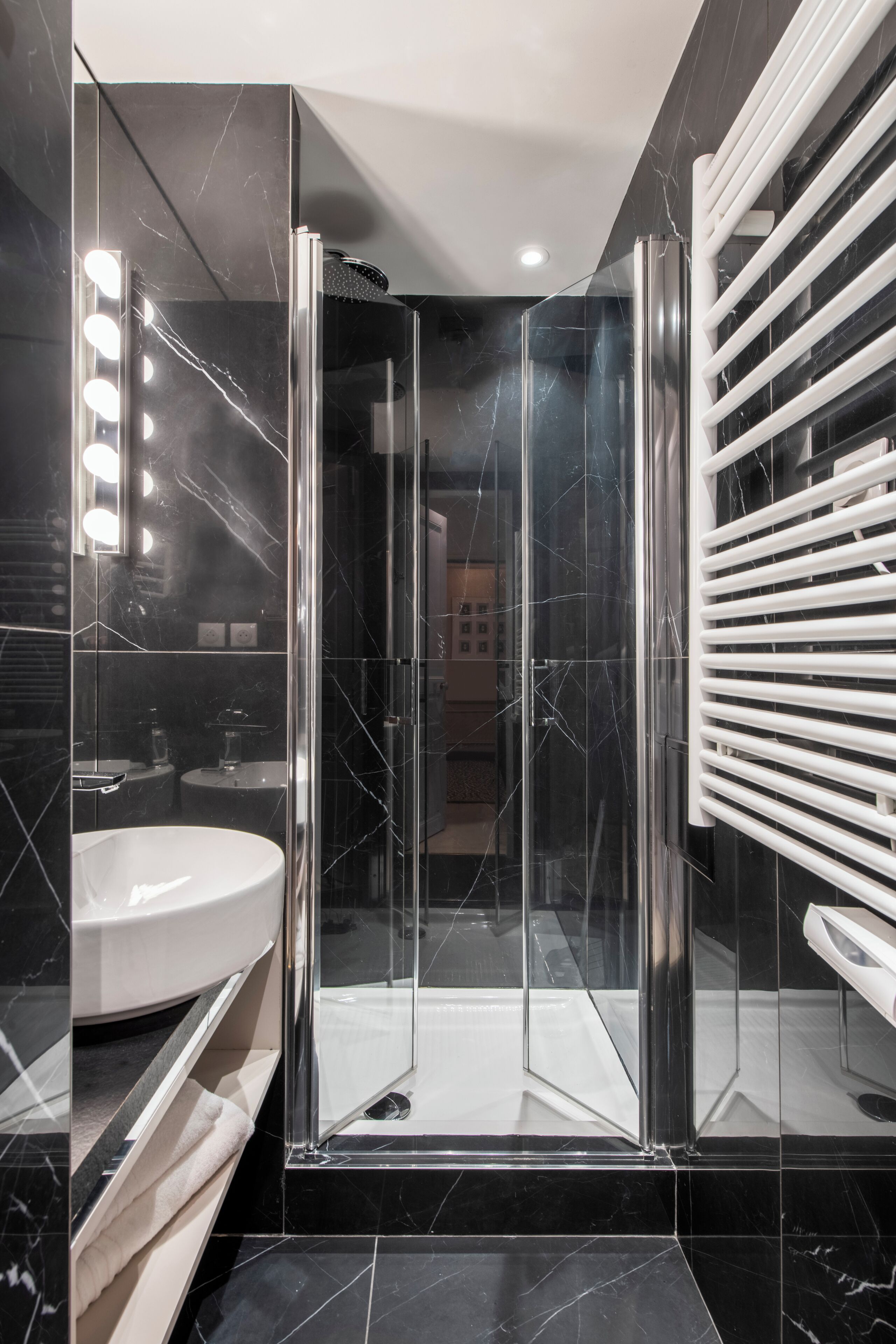 Un baño moderno con ducha de vidrio, lavamanos blanco y tocador con espejo.