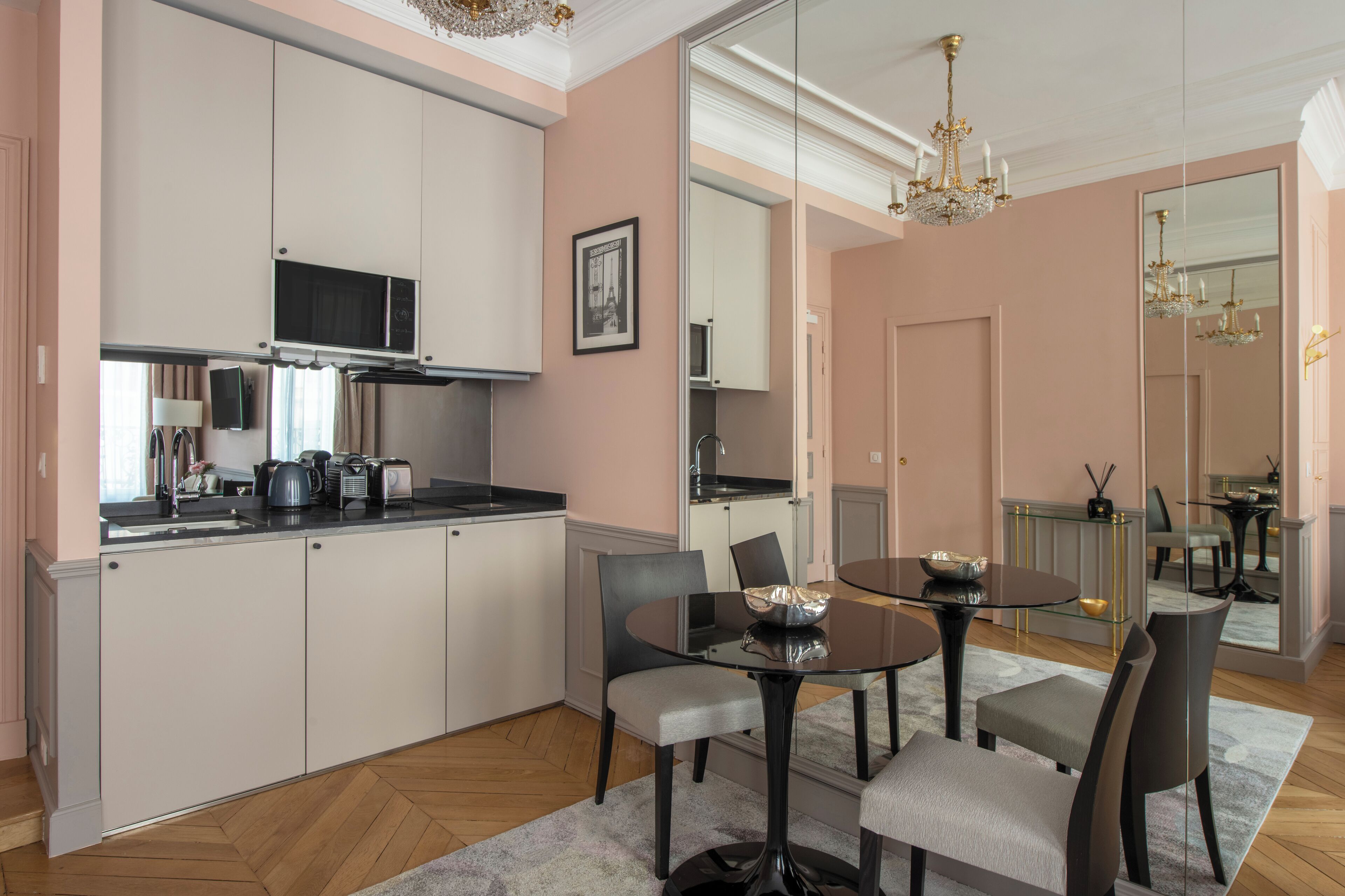 A modern kitchen with white cabinets, a microwave, and a dining area with a round table and chairs.