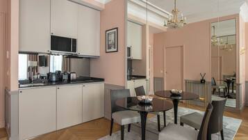 A modern kitchen with white cabinets, a microwave, and a dining area with a round table and chairs.