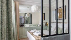 Habitación de hotel con cama, espejo, candelabro y vistas al exterior.