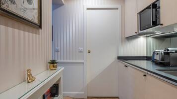 Une cuisine étroite avec un sol décoré d’un motif en chevrons, un four à micro-ondes, un grille-pain et une œuvre d’art représentant un papillon, encadrée et accrochée au mur.