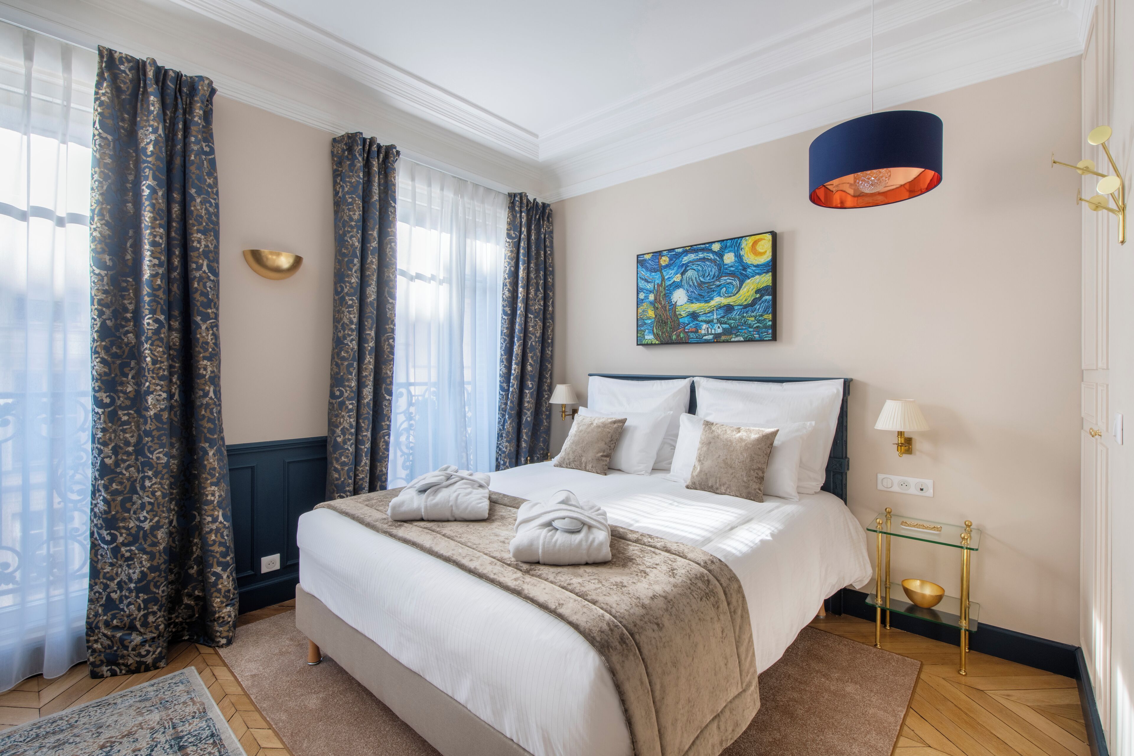 Une chambre d’hôtel avec un grand lit, un tableau au mur, une lampe et une table de chevet.