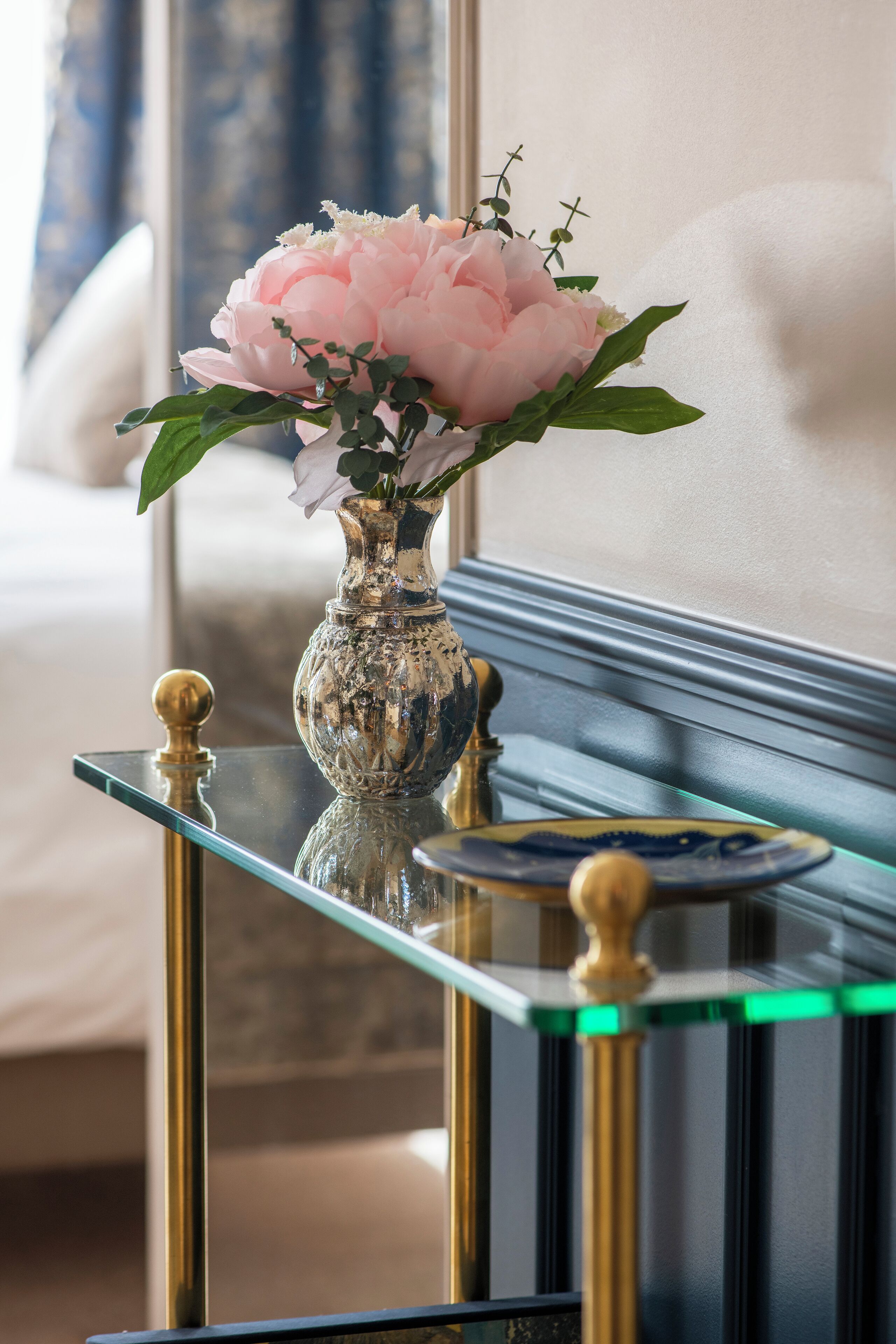 A glass table with a vase of flowers and a plate.