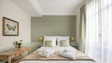 A neatly made bed with pillows, a bedside table with a vase of flowers, and a framed butterfly artwork on the wall.