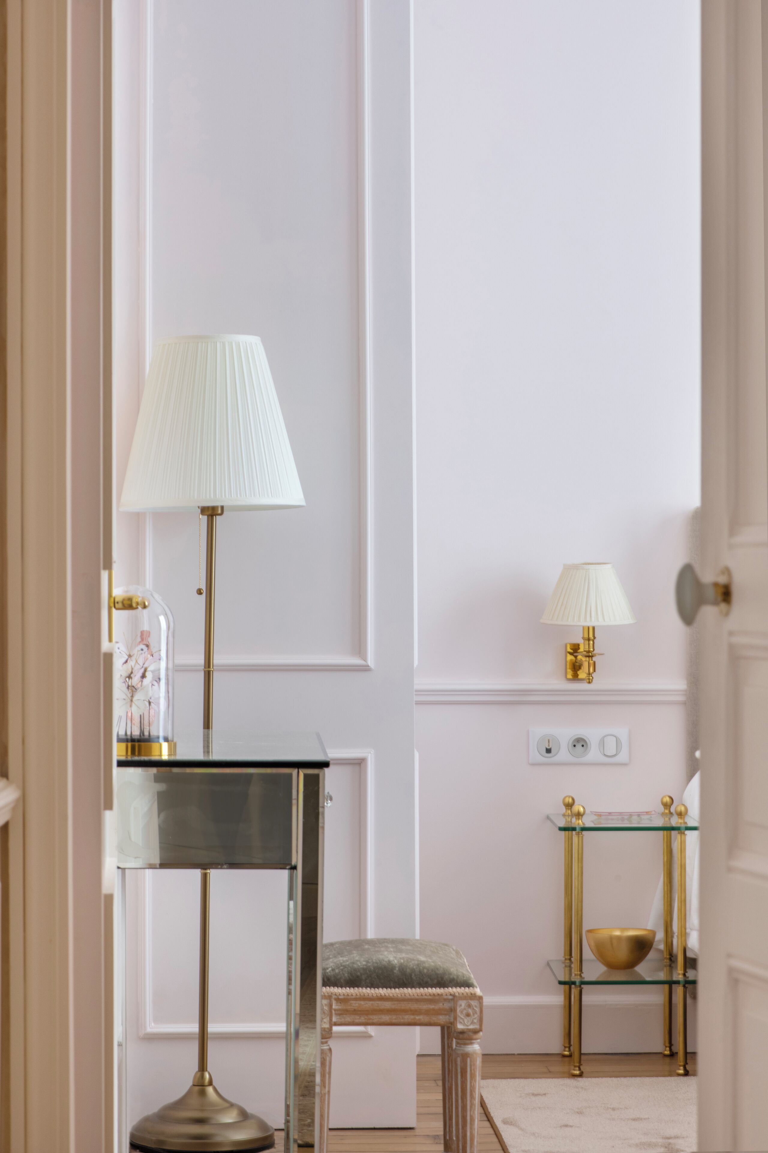 Una habitación con una mesa de vidrio, una banca, una lámpara y una lámpara de pared.