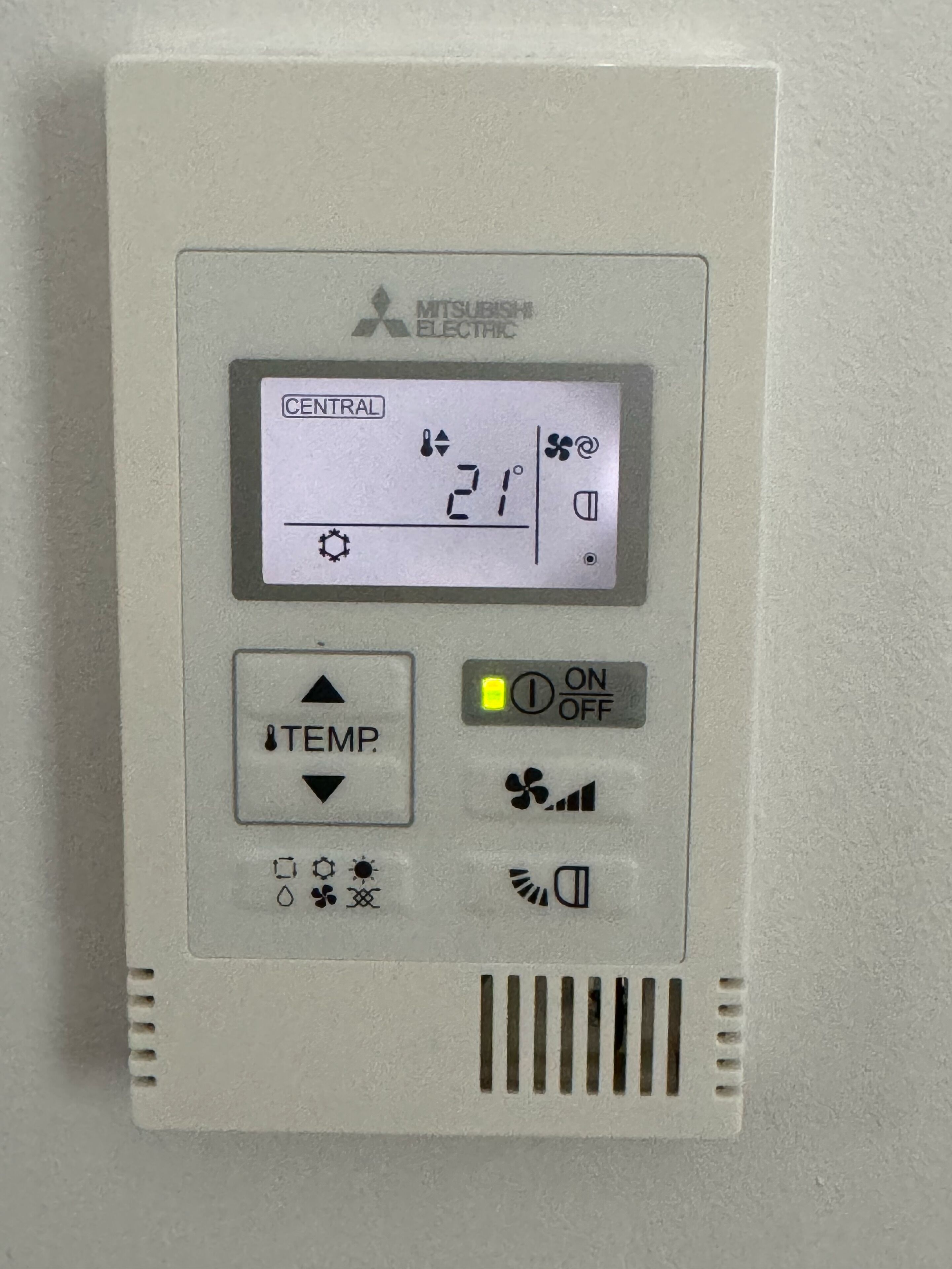 Un thermostat Mitsubishi Electric doté d’un écran numérique indiquant 21 °C, de boutons de réglage de la température et d’un interrupteur marche/arrêt.