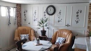 Una habitación con dos sillones de cuero, una mesa redonda, un reloj y paneles decorativos en la pared.