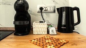 Un plan de travail de cuisine avec une machine à café, une bouilloire et un panier en osier.