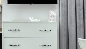 Un meuble de rangement blanc pour appareils électroniques, avec un téléviseur à écran plat affichant le mot « NETFLIX » en lettres rouges.
