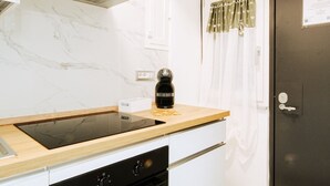 Une cuisine moderne dotée d’un four encastré, d’une machine à café noire et d’un dosseret en marbre.