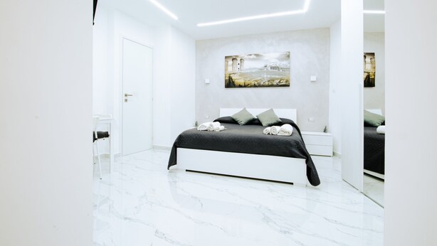 Une chambre moderne avec un grand lit, des murs blancs et un sol en marbre.