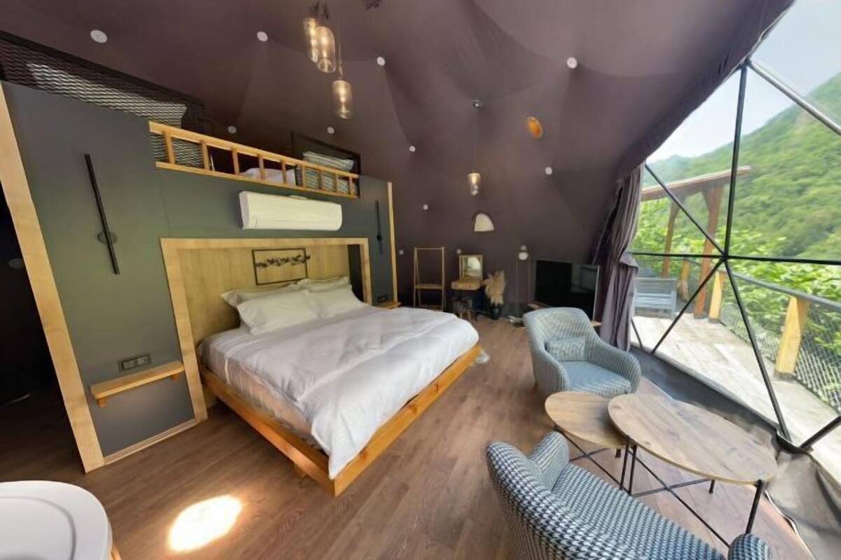 Une chambre avec un grand lit, un canapé, une petite table et une vue sur l’extérieur.