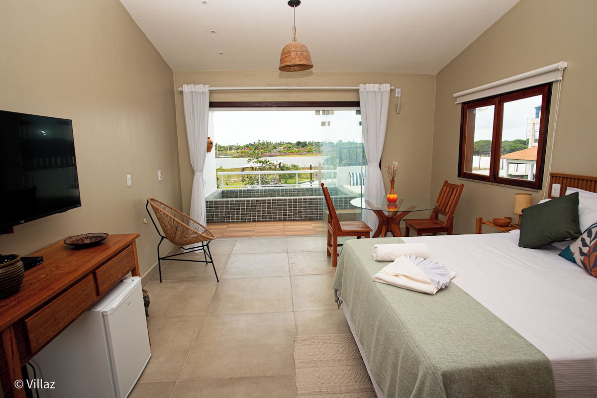 Une chambre d’hôtel comprenant un lit, un bureau avec une télévision, un balcon avec vue et un coin repas.