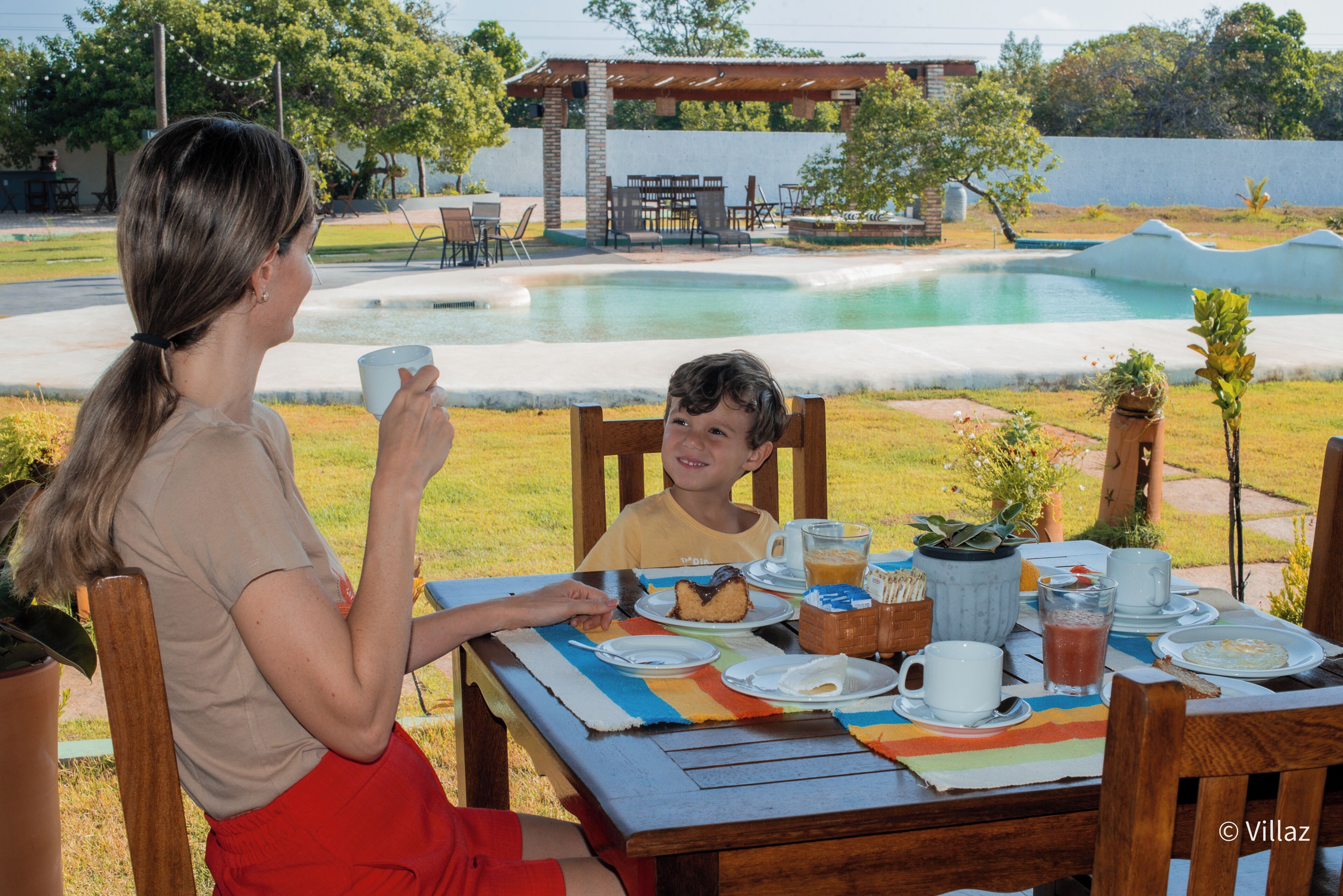 A dining table set outdoors with a pool in the background.