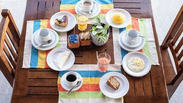 A wooden table set with plates of food, cups, and a striped tablecloth.