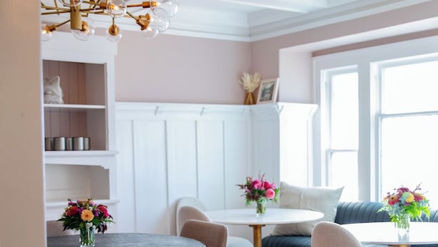 A dining area with a round table, chairs, a chandelier, and a window with natural light. - The Compass McMinnville (McMinnville)