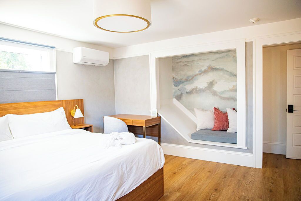 A modern hotel room with a wooden bed, a desk, and a large window.
