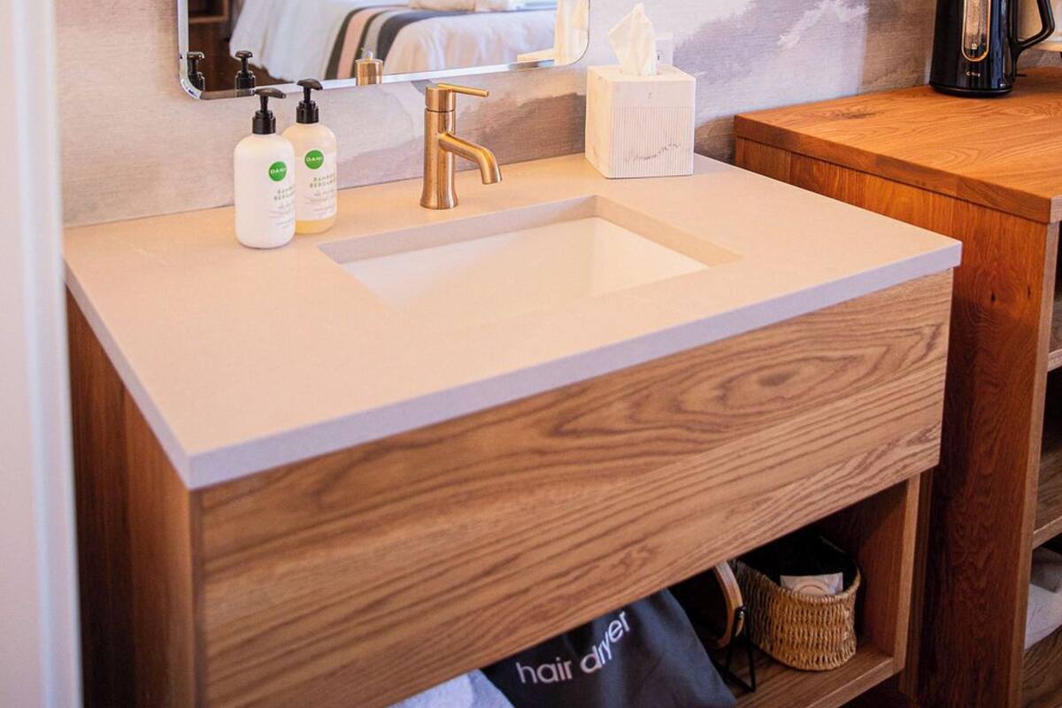A modern bathroom with a large mirror, a white sink, and wooden cabinetry.