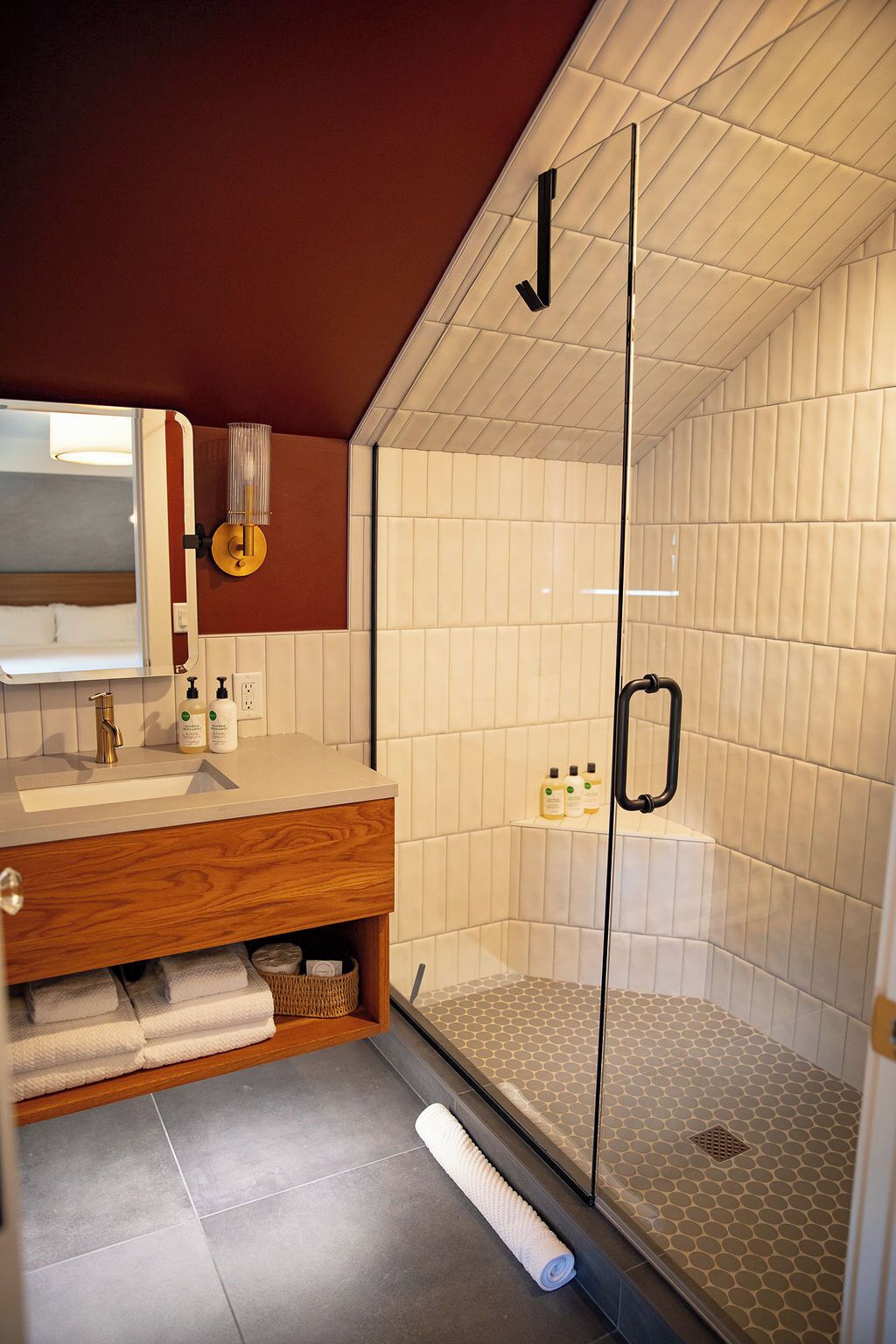 A modern bathroom with a glass-enclosed shower, a wooden vanity, and a mirror.