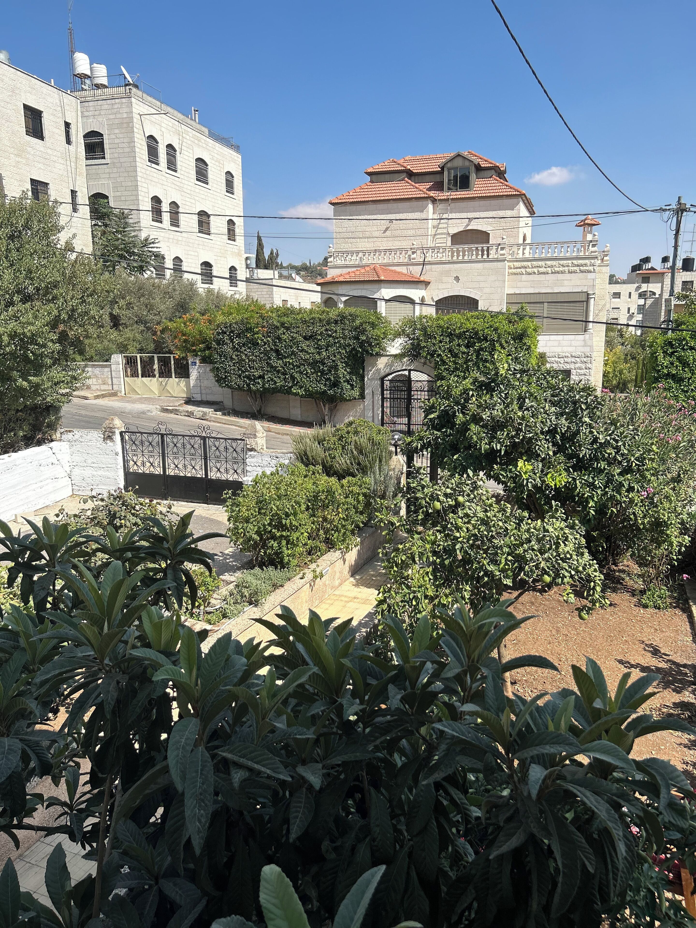 A residential area with a gated entrance, lush greenery, and buildings with traditional architecture.
