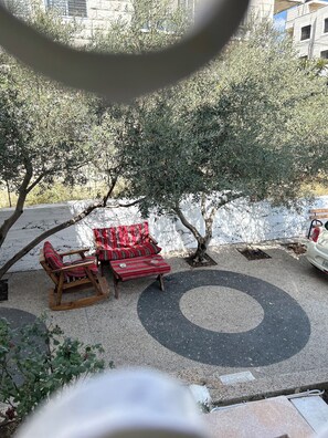 An outdoor seating area with a circular design, a white wall, and a tree. - OliveTreeHostel (Ramallah)