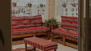 A cozy seating area with patterned cushions and a bench, a small table, and a hanging plant. - OliveTreeHostel (Ramallah)
