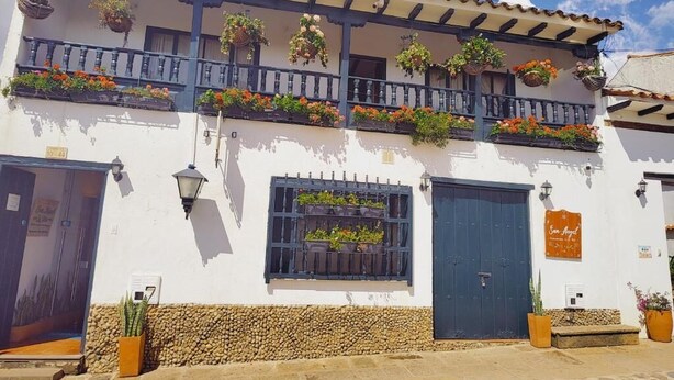 A two-story building with balconies adorned with hanging flower baskets. - One and a half blocks from the main square! Nice and cozy hotel. (Villa de Leyva)