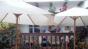 An outdoor patio with wicker chairs and tables, covered by umbrellas, and surrounded by potted plants. - One and a half blocks from the main square! Nice and cozy hotel. (Villa de Leyva)