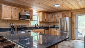 A spacious kitchen with wooden cabinets, a stainless steel refrigerator, and a granite countertop.