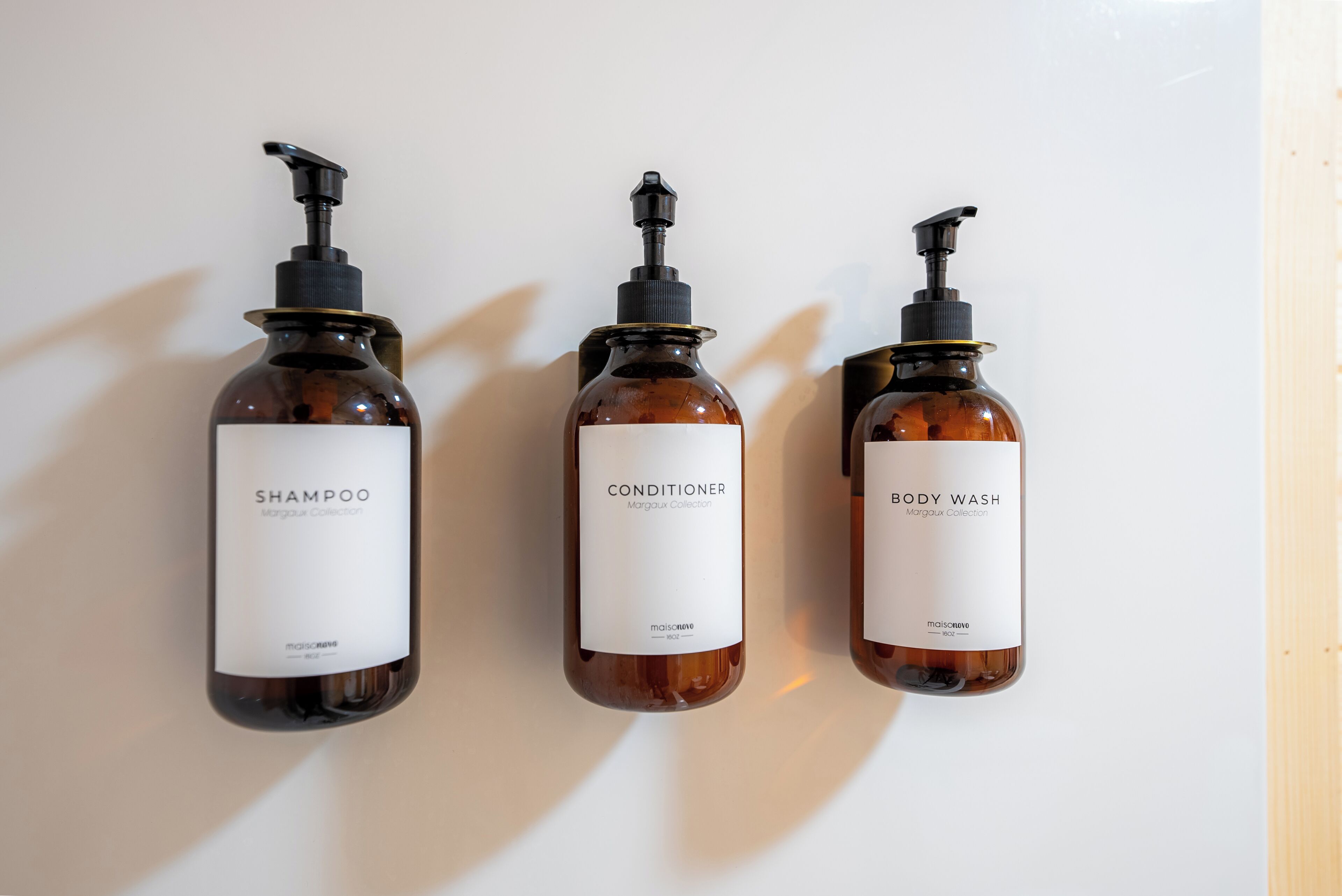 Three bottles of shampoo, conditioner, and body wash from the Margaux Collection.